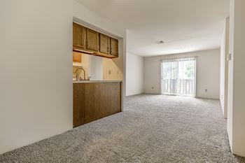 A room with a grey carpet and wooden cabinets